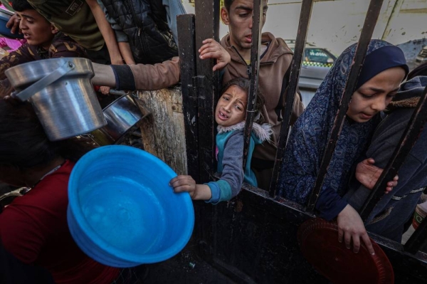 Displaced Palestinians gather to collect food donated by a charitable youth group in Rafah, Gaza, on March 12