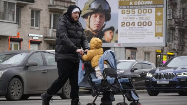 A man and his child pass an army recruitment poster in Moscow