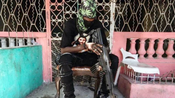 A man sits with a machine gun in Port-au-Prince. — courtesy Getty Images