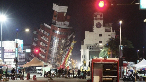 Emergency personnel stand in front of a partially collapsed building leaning over a street in Hualien on April 3, 2024, after a major earthquake hit Taiwan's east coast