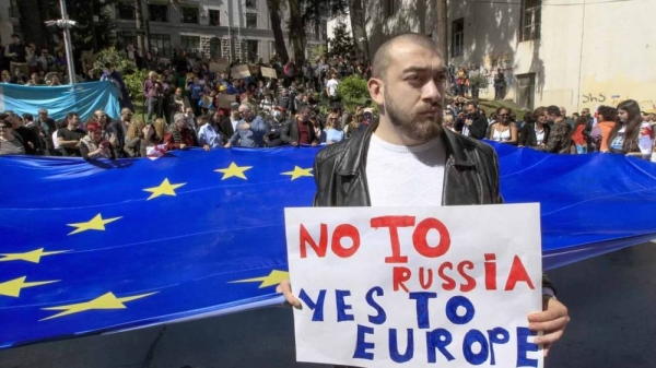 A man stands in front of protestors with a giant EU flag outside the parliament building in Tbilisi, Georgia, on Monday, April 15, 2024