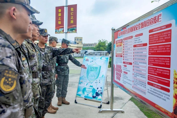 Chinese soldiers look at a poster promoting national security in the southwestern city of Beihai on National Security Education Day on April 15, 2024