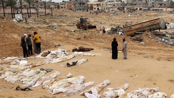 People gather near bodies lined up for identification after they were unearthed from a mass grave found in the Nasser Medical Complex in the southern Gaza Strip