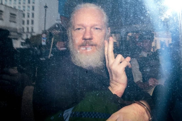 Julian Assange gestures to the media from a police vehicle on his arrival at Westminster Magistrates court on April 11, 2019 in London, England