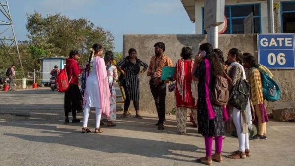 Job aspirants speak to a hiring agent outside the Foxconn factory near Chennai