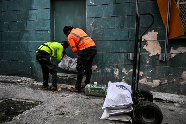 Workers put bags of sand at the back door of a shop on Sunday in preparation for the arrival of Hurricane Beryl in Bridgetown, Barbados