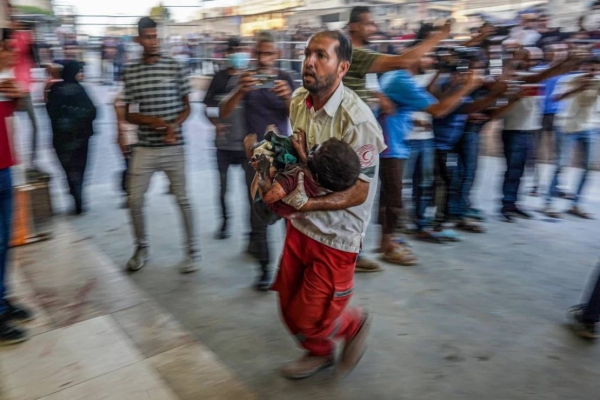 A paramedic carries a wounded child to the emergency ward in Khan Younis, in the southern Gaza Strip, on July 9,