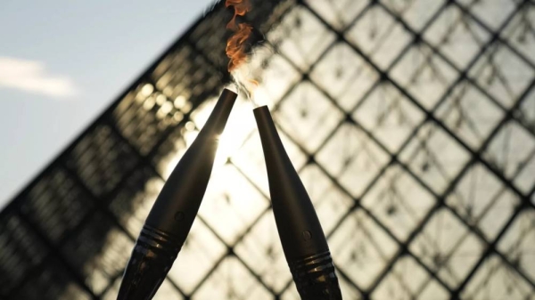 The Olympic torch is seen during a relay in the courtyard of the Louvre Museum Sunday, July 14, 2024 in Paris
