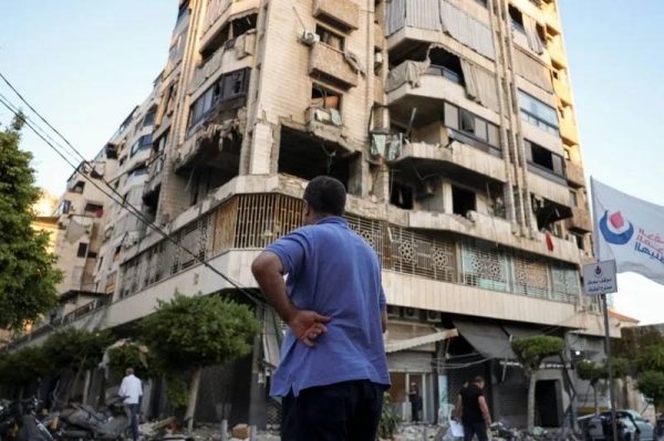 A Beirut resident stands in front of a building damaged in an Israeli air strike last week
