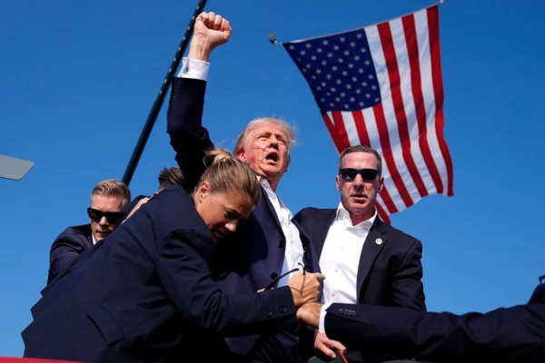 Former President Donald Trump, with blood on his face, raises his fist to the crowd as he is surrounded by Secret Service agents at his campaign rally in Butler, Pennsylvania