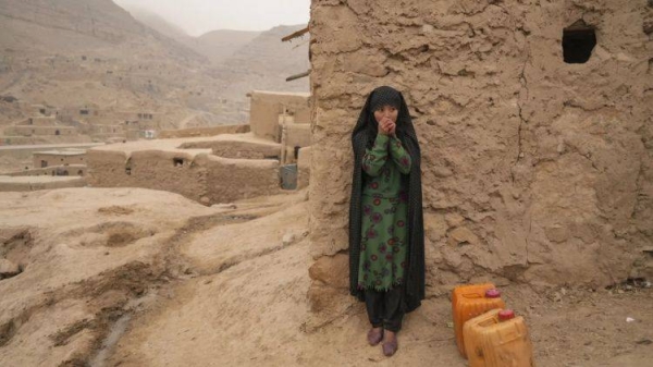 An Afghan girl warms up her hands as she is resting from carrying the water in Balucha, Afghanistan, Monday, Dec. 14, 2021