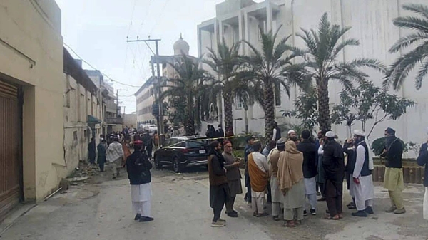 People gather near the site of a deadly suicide bombing in northwestern Pakistan, on February 28, which tore through a mosque at a pro-Taliban seminary