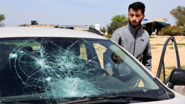 Basel Adra looks at a grey car with its window smashed