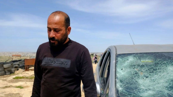 Hamdan Ballal stands outside his car, which was vandalized by Israeli settlers in his village in the occupied West Bank on Monday