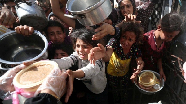 Palestinian children receive food cooked by a charity kitchen, in Beit Lahia, northern Gaza Strip, on Sunday
