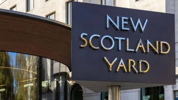 A black sign that reads New Scotland Yard in silver lettering