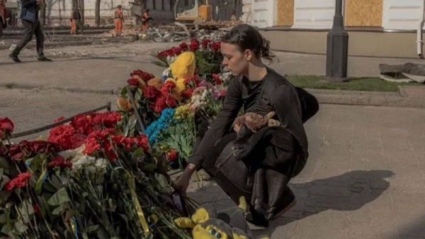 A woman lays flowers and a soft toy at a makeshift memorial on the site of a missile attack in Sumy, northeastern Ukraine, on April 14, 2025
