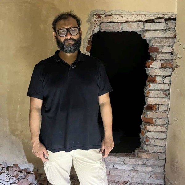 Mir Ahmad Bin Quasem stands in a detention center looking at the camera