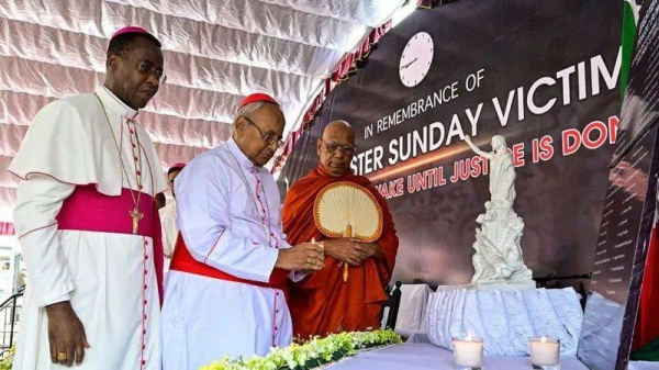 The head of Sri Lanka's Roman Catholic church Cardinal Malcolm Ranjith (C) places a candle in front of a plaque as he pays respect to the victims of the 2019 Easter Sunday bombings on the 6th anniversary of the suicide attacks, as Vatican ambassador to Colombo Archbishop Brian Udaigwe (L) and Buddhist monk Omalpe Sobitha watch outside the St. Anthony's church in Colombo on April 21, 2025.