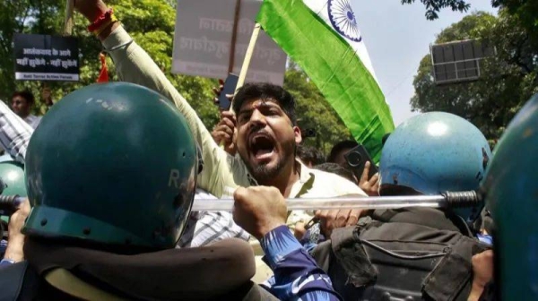 A demonstrator shouts as he is stopped by police during a protest against in New Delhi, India