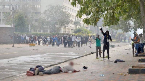 Student journalist Ademba Allans trying to reach David Chege and another casualty lying on the ground after the shooting