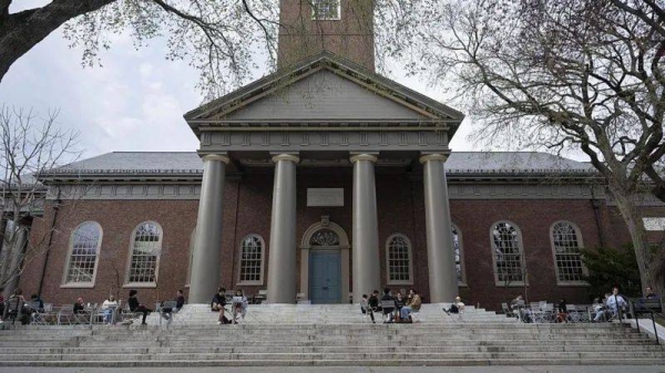 Students sit on steps at Harvard outside a large academic brick building