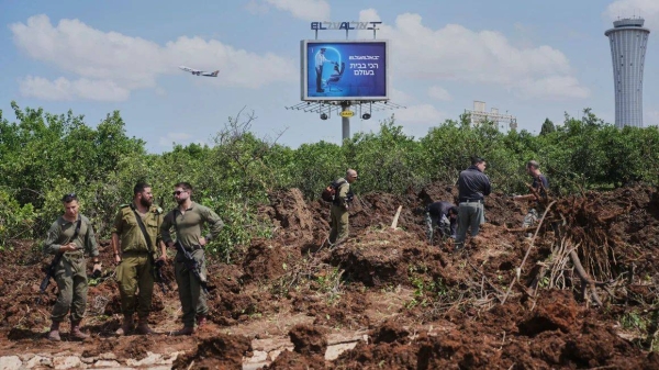 Israeli security forces inspect the site where a projectile fired by Yemen's Houthi rebels landed, near Ben Gurion Airport on Sunday