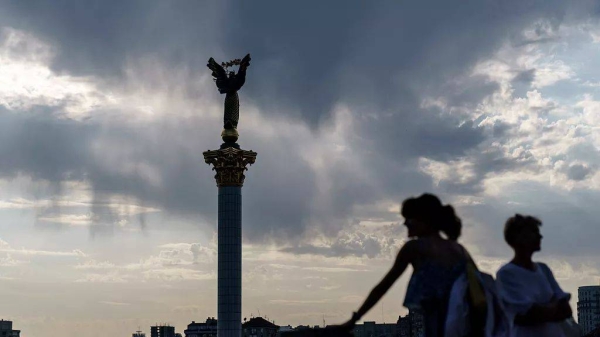 The sun sets behind the Independence Monument overlooking Maidan Square on the country's National Flag Day, Tuesday, Aug. 23, 2022, in Kyiv, Ukraine