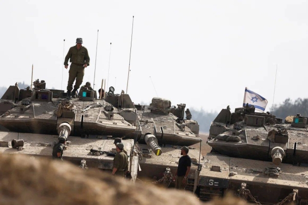 Israeli soliders stand next tanks parked near the Israel-Gaza border, amid the ongoing conflict between Israel and Hamas, in Israel on Monday