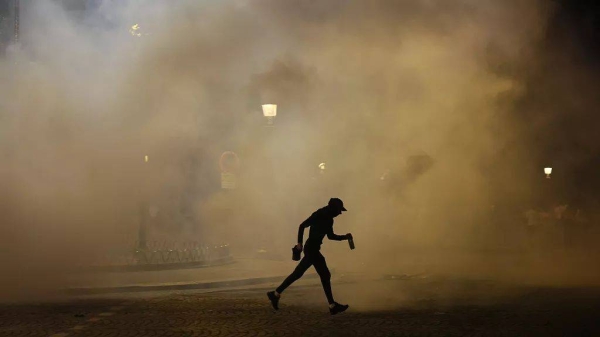 A man walks past teargas during incidents after the Champions League final soccer match between Paris Saint-Germain and Inter Milan in Paris, 1 June, 2025