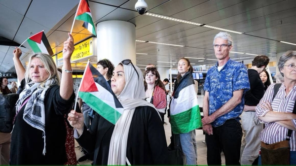 People wave Palestinian flags as participants in the 'Global March to Gaza' depart from Schiphol Airport in The Netherlands en route to Egypt on Wednesday.