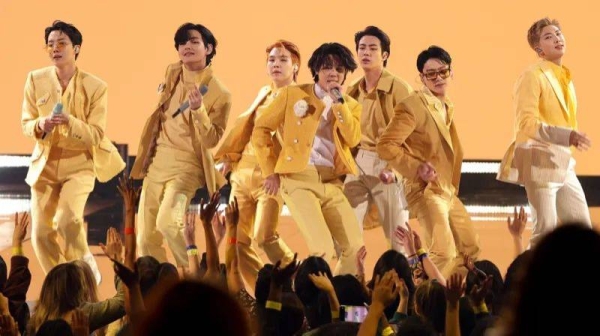 BTS wearing yellow suits, pictured on stage at the American Music Awards in 2021