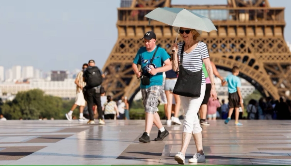 A tourist holds an umbrella as protection from the sun during a heatwave near the Eiffel Tower, in Paris, on June 30, 2025. 