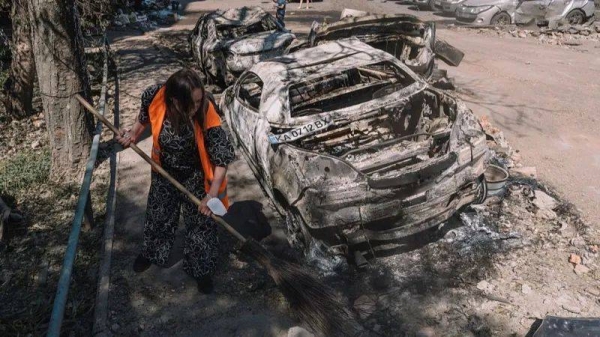 A woman sweeps the streets after damage from a Russian air strike in a residential area of Kyiv, Ukraine on 4July 2025