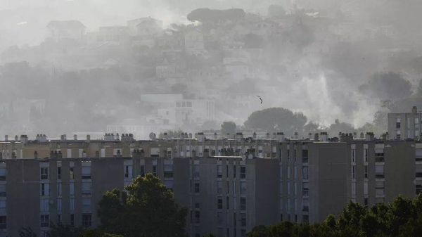 Smoke rises behind buildings during wildfire Tuesday, July 8, 2025 in La Castellane district of Marseille, southern France