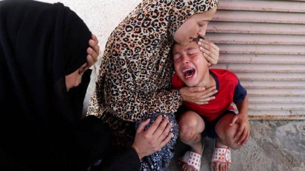 A woman comforts a child at al-Aqsa Hospital in Deir al-Balah, after medics said at least 15 people were killed in an Israeli strike at a roundabout, in central Gaza.