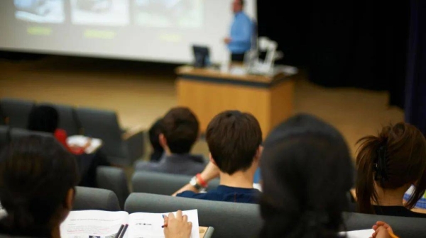 A picture taken in a university lecture hall of several rows of students