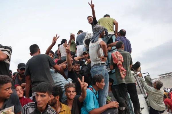 Palestinians climb in the back of a truck on a coastal path west of Beit Lahiya, after managing to get aid parcels when aid trucks entered the Israel-besieged Gaza Strip from the northern Zikim crossing