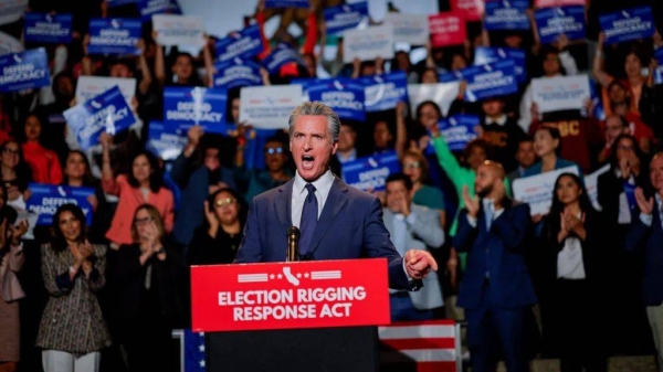 California Governor Gavin Newsom shouts behind a podium that bears a sign that says Election Rigging Response Act. A crowd of supporters holds signs behind him