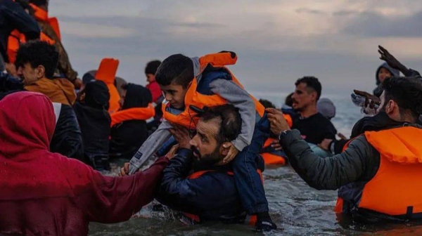 Migrant families wade into the sea in an attempt to board a small boat on 12 August 2025 in Gravelines, France