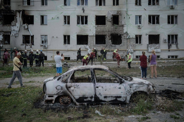 Ukrainian rescuers, city workers and local residents gather in front of a destroyed residential building after an air attack in Kharkiv, on Monday.