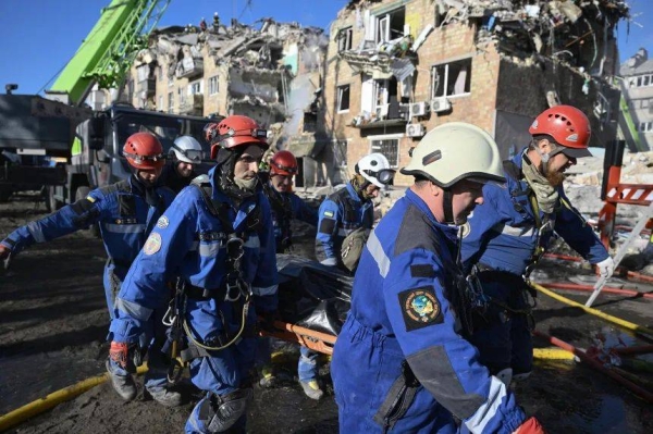 Ukrainian rescuers carry the body of a victim recovered during a search and rescue operation at the site of a residential building heavily damaged following a Russian missile strike on Thursday