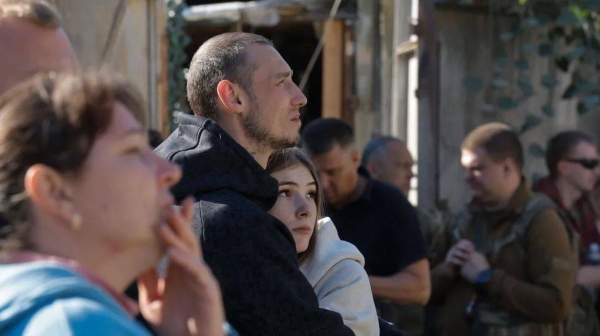 A man and a woman embrace each other - they are standing outside near the five-storey building in Ukraine destroyed in a missile strike