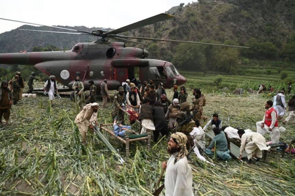 Afghan volunteers and Taliban security personnel work to move injured people near a military helicopter following earthquakes in the Mazar Dara village of Nurgal, a district of the Kunar Province, in Eastern Afghanistan, on Se