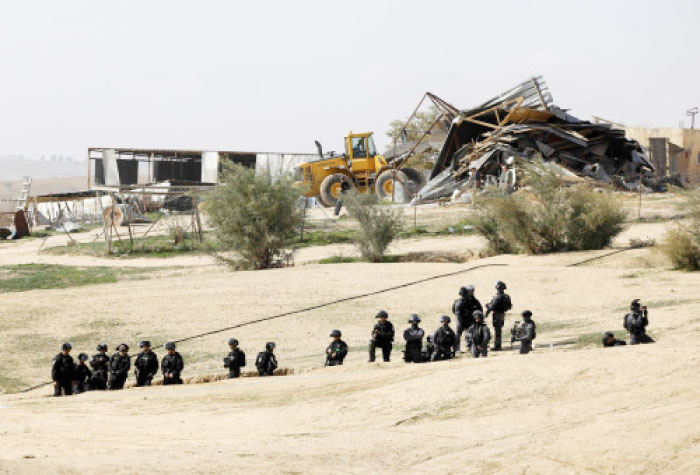 Israeli policemen stand guard as bulldozers demolish homes in the Bedouin village of Umm Al-Hiran, which is not recognized by the Israeli government, near the southern city of Beersheba, in the Negev desert, Wednesday. — AFP