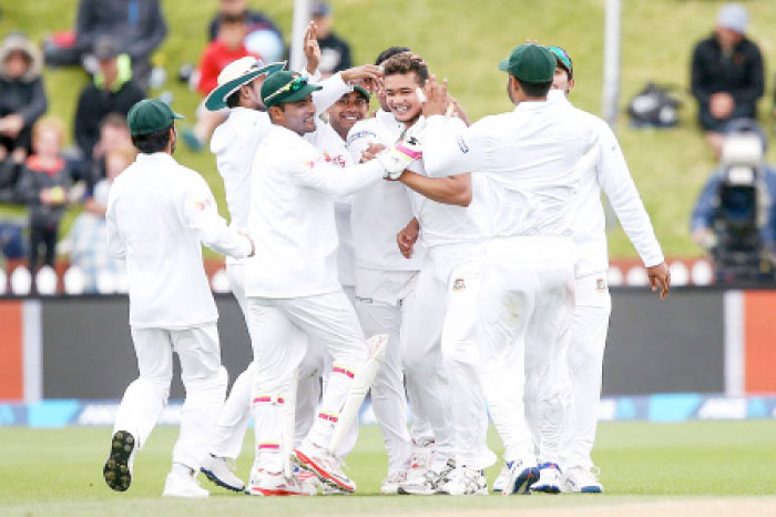 Taskin Ahmed is surrounded by teammates after claiming Kane Williamson for his maiden Test wicket in Wellington Saturday.