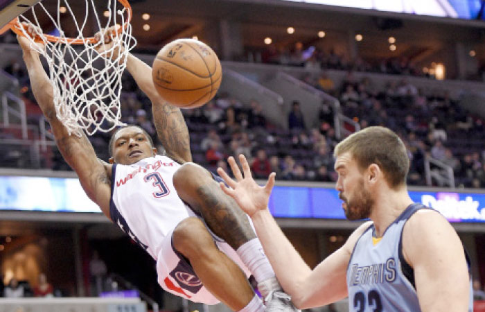 Washington Wizards’ guard Bradley Beal hangs on the rim after his dunk against Memphis Grizzlies’ center Marc Gasol of Spain during the second half of their NBA game in Washington Wednesday. - AP