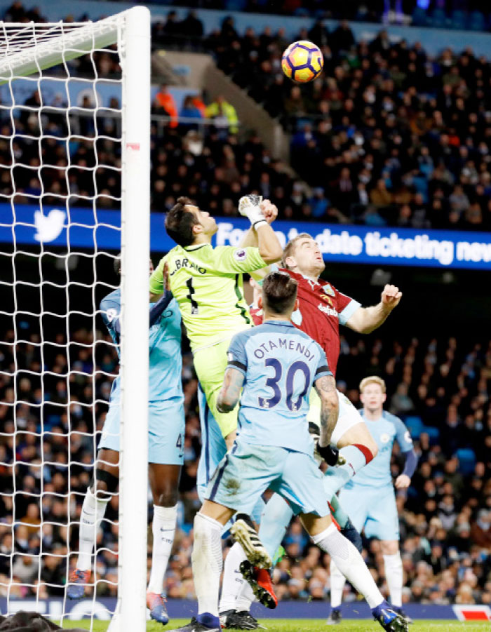 Manchester City goalkeeper Claudio Bravo (L) attempts to punch the ball out before Burnley’s Ben Mee scores during their English Premier League match in Manchester Monday. - AP