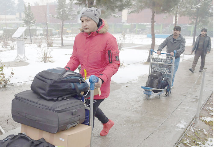 Afghan refugees who have been deported from Germany arrive with their belongings at the international airport in Kabul on Tuesday. — AFP
