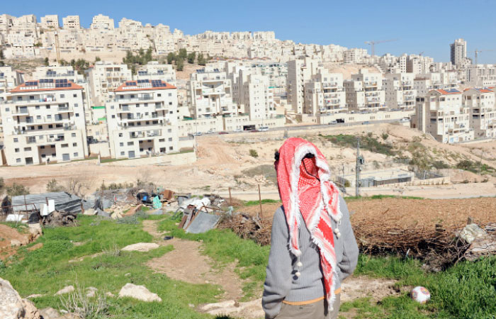 A Palestinian stands on his property overlooking the Israeli settlement in West Bank in this file photo.